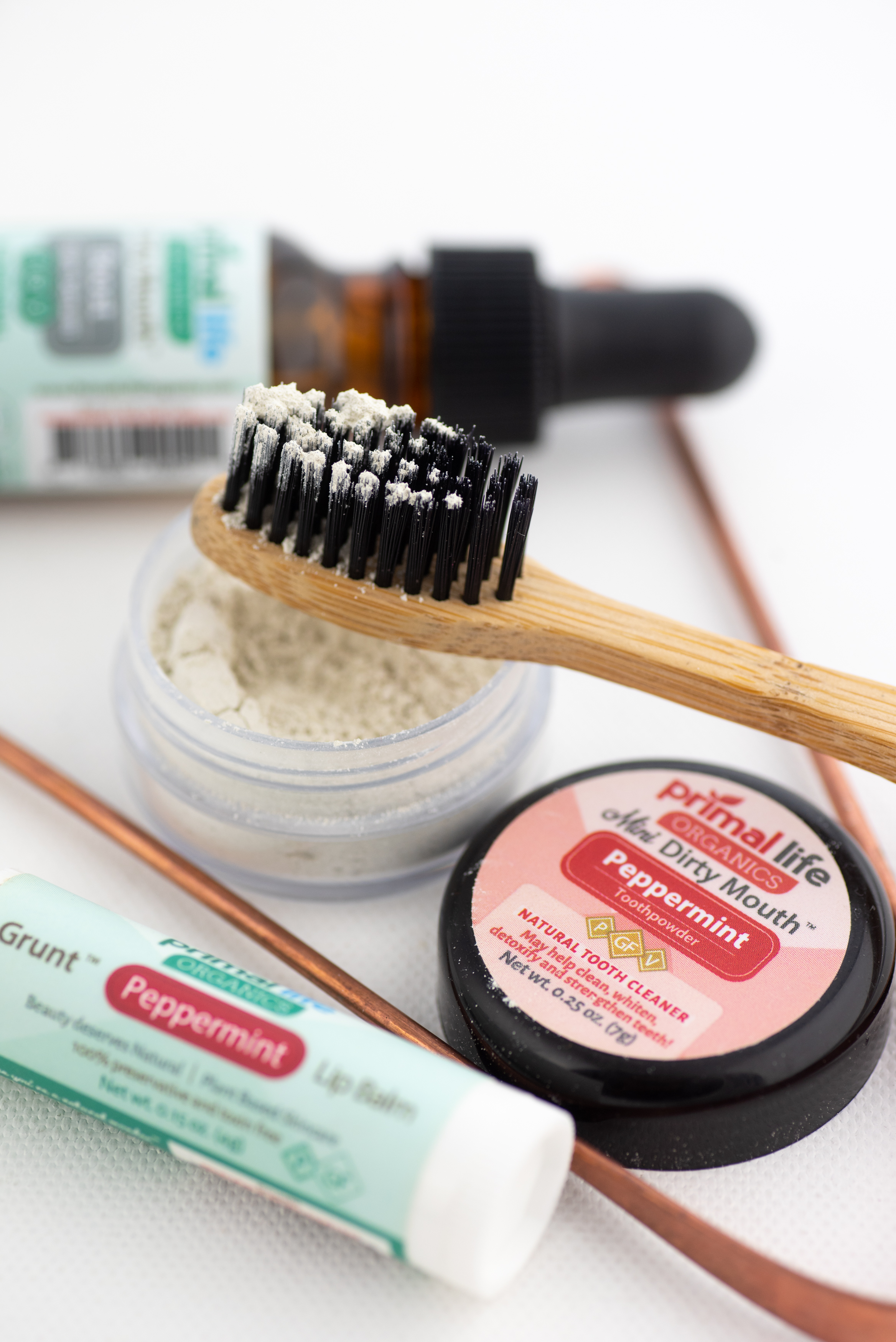 Close-up of Dental Starter Kit, focusing on Dirty Mouth Toothpowder on charcoal ion toothbrush